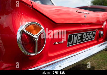 Le luci posteriori circolari segmentate a scomparsa su una Ford Cortina Deluxe 1965 Mark 1 (MK1) di colore rosso brillante in mostra a un evento di auto d'epoca a Storringto Foto Stock