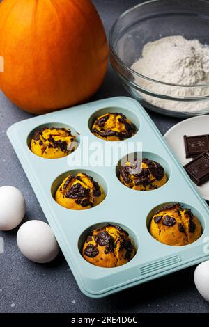 Muffin di zucca cotti nello stampo in silicone al tavolo con gli ingredienti. Foto Stock