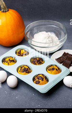 Muffin di zucca cotti nello stampo in silicone al tavolo con gli ingredienti. Foto Stock