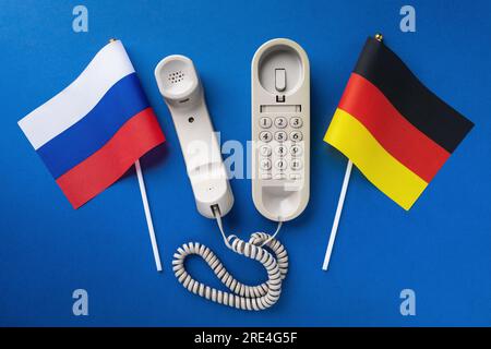 Vecchio telefono e due bandiere su sfondo blu, un concetto sul tema delle conversazioni telefoniche tra Russia e Germania Foto Stock