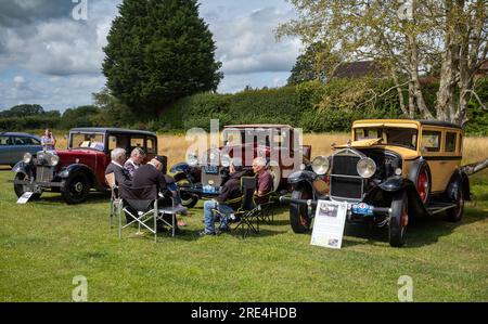 Un gruppo di appassionati di sesso maschile si siede sulle sedie da picnic di fronte alle loro immacolate auto d'epoca degli anni '1930 in mostra in una mostra di auto d'epoca a Storrington, West Foto Stock