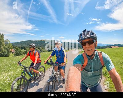 Gruppo di amici anziani attivi che si divertono durante un tour in bicicletta nelle Alpi Allgau vicino a Oberstaufen, Baviera, Germania Foto Stock