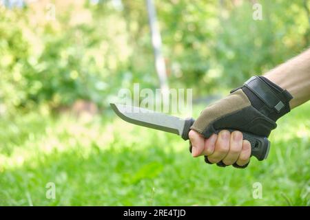 coltello militare tattico in mano con guanti all'aperto Foto Stock
