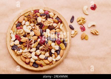 Frutta secca e uva passa assortita in vassoio di legno su sfondo rustico naturale. Foto Stock