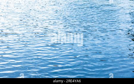 Superficie d'acqua lucida con riflessi del cielo blu, texture astratta e naturale di sfondo Foto Stock