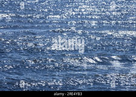 Acqua di mare blu brillante con riflessi della luce del sole, texture naturale di sfondo Foto Stock