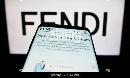 Telefono cellulare con sito web della società di moda italiana Fendi S.r.l. sullo schermo davanti al logo aziendale. Mettere a fuoco in alto a sinistra sul display del telefono. Foto Stock