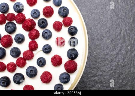 Torta al formaggio, fragole e lamponi su uno strato piatto bianco cremoso. Cucinare a casa. Ricetta e attività di cottura con pasticceria e panetteria. Cheesecake con Foto Stock