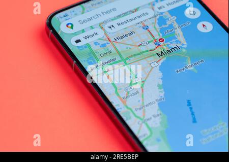 New York, USA - 21 luglio 2023: Traffico automobilistico su Miami google Maps sullo schermo dello smartphone vista ravvicinata con sfondo rosso Foto Stock