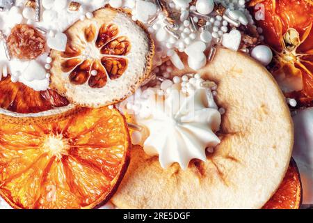 Primo piano con decorazioni per dolci pasquali. Torta alla frutta cotta, fette di arance secche, pere, meringa bianca, caramelle cosparse per primo piano. Gustoso kulic al forno per le feste Foto Stock