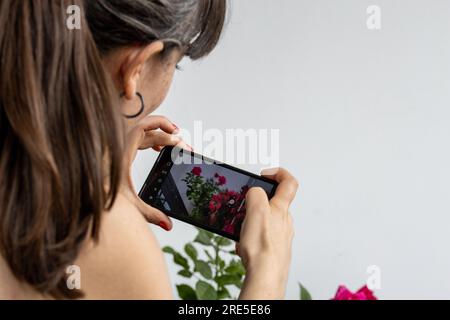 l'influencer scatta foto di mazzi di fiori rossi e piante durante la fioritura primaverile. Foto per i social network e per il giardinaggio e una passione per il giardinaggio Foto Stock