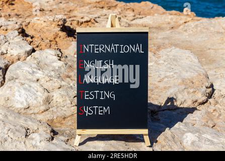 Simbolo IELTS. Concetto di parola IELTS sistema internazionale di test in lingua inglese su lavagna nera. Splendido sfondo in pietra. Business IELTS intern Foto Stock