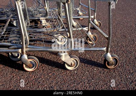 Una pila di macchine per la spesa si trova su un terreno accidentato del parcheggio. I carrelli della spesa subiscono molti abusi per essere mandati, investiti, lasciati fuori Foto Stock