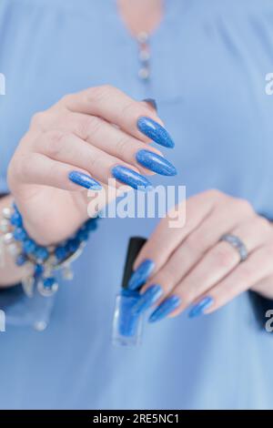 La bella mano della donna con unghie lunghe e manicure azzurro Foto Stock