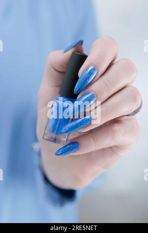 La bella mano della donna con unghie lunghe e manicure azzurro Foto Stock