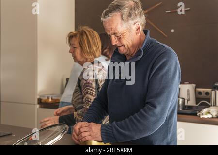 Adulto anziano che prepara il pranzo al bancone della cucina Foto Stock