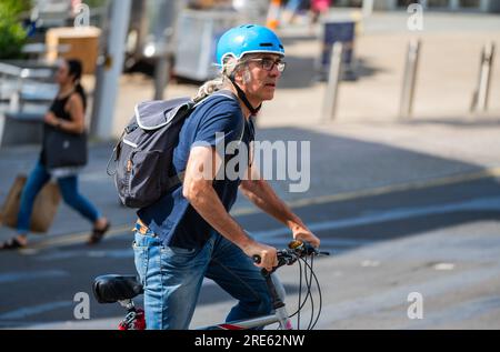 Uomo di mezza età e ciclista, in bicicletta con casco e zaino in estate, Regno Unito. Foto Stock