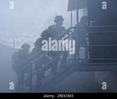 Hohenfels, Germania. 21 luglio 2023. Cadetti ufficiali dell'esercito britannico della Royal Military Academy Sandhurst assaltano un edificio in fumo durante Dynamic Victory 23-2 presso il Joint Multinational Readiness Center, 21 luglio 2023 vicino Hohenfels, Germania. Credito: SPC. Leonard Beckett/US Army Photo/Alamy Live News Foto Stock