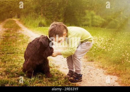 Bambino Cyte con un cane che cammina nel parco estivo. Bambino che gioca con il cane in natura. Foto Stock