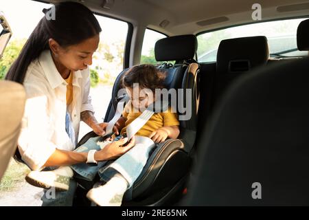 Mamma coreana seduta sul bambino in un posto sicuro in automobile Foto Stock