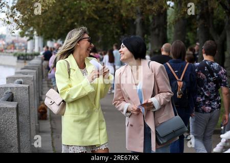 Due donne felici che ridono durante una passeggiata in città in estate Foto Stock