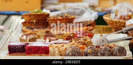 Banco dolciario con una varietà di dessert, palle di punch ricoperte di cocco grattugiato, brownie cosparse di mandorle e semi di papavero Foto Stock