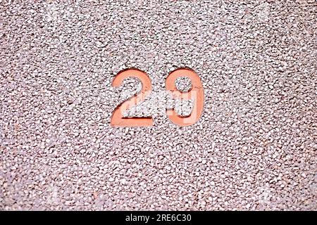 Number 29, twenty-nine, embossed orange on simple textured background. Foto Stock