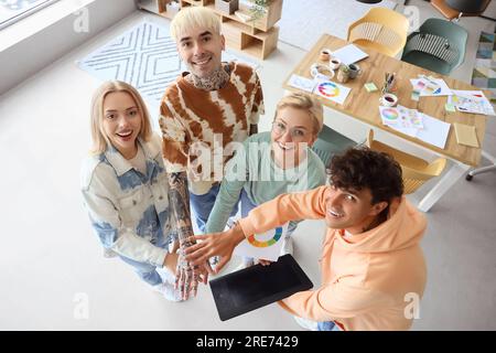 Team di grafici che mettono insieme le mani in ufficio Foto Stock