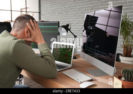 Programmatore maschio maturo e stressato che lavora in ufficio Foto Stock