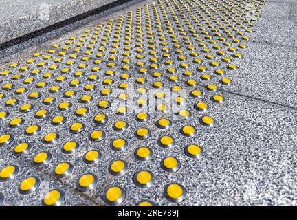 scala in granito grigio con indicatori tattili gialli per non vedenti Foto Stock