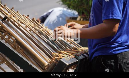 Un uomo sta giocando ad angklung. Si tratta di uno strumento musicale multitonale che si è sviluppato dal popolo Sundanese. Angklung è fatto di bambù Foto Stock