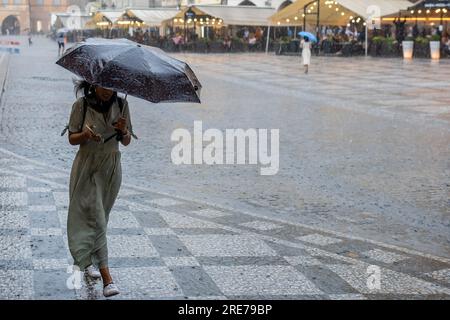 Praga, Repubblica Ceca. 25 luglio 2023. Una giovane donna cammina con un ombrello durante la pioggia battente lungo la Piazza della città Vecchia a Praga. Più di 15 millimetri di pioggia durante le 24 ore ha concluso l'attuale stagione secca nella Repubblica Ceca. (Foto di Tomas Tkacik/SOPA Images/Sipa USA) credito: SIPA USA/Alamy Live News Foto Stock