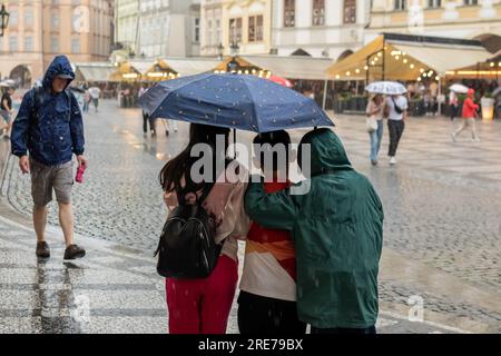 Praga, Repubblica Ceca. 25 luglio 2023. La famiglia si nasconde sotto l'ombrello durante la forte pioggia lungo la Piazza della città Vecchia a Praga. Più di 15 millimetri di pioggia durante le 24 ore ha concluso l'attuale stagione secca nella Repubblica Ceca. (Foto di Tomas Tkacik/SOPA Images/Sipa USA) credito: SIPA USA/Alamy Live News Foto Stock