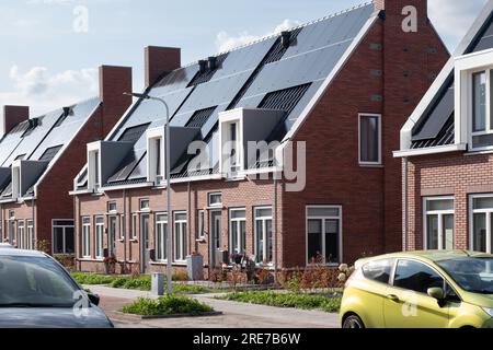 Strada con moderne case monomarca di nuova costruzione con pannelli solari sul tetto nei Paesi Bassi. Energia sostenibile. Generazione di energia elettrica Foto Stock