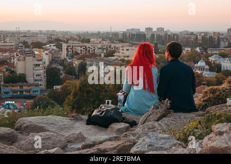 Una giovane coppia che si affaccia sulla storica città di Plovdiv, Bulgaria al tramonto, dalla cima di un antico muro di pietra sulla collina di Nebet Tepe Foto Stock