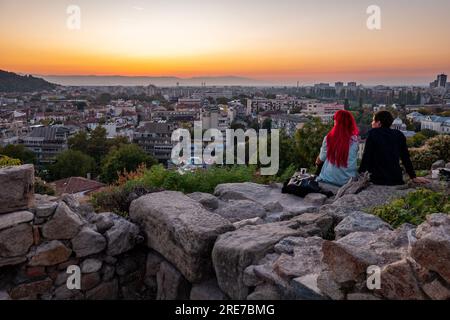 Una giovane coppia che si affaccia sulla storica città di Plovdiv, Bulgaria al tramonto, dalla cima di un antico muro di pietra sulla collina di Nebet Tepe Foto Stock