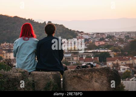 Una giovane coppia che si affaccia sulla storica città di Plovdiv, Bulgaria al tramonto, dalla cima di un antico muro di pietra sulla collina di Nebet Tepe Foto Stock