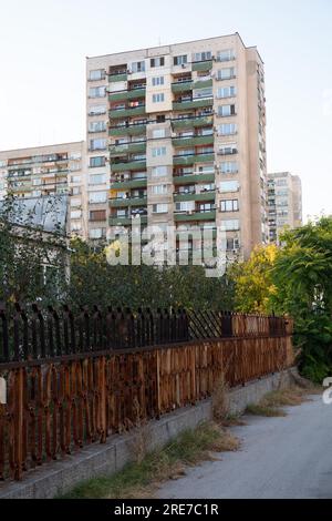 Una recinzione in ferro battuto estremamente arrugginito e un alto edificio di appartamenti in un quartiere residenziale di Plovdiv, Bulgaria Foto Stock