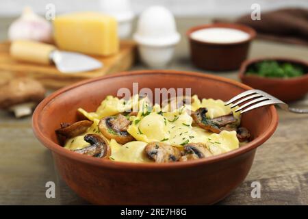 Deliziosi ravioli con funghi e forchetta su tavolo in legno, primo piano Foto Stock