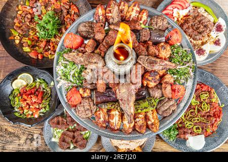 Piatto tradizionale turco e arabo di Kebab Vali all'interno di Adana, Urfa, pollo, agnello, fegato e manzo su pane su sfondo di legno Foto Stock