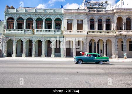 Case Malecon a la Havana con auto che guidano per strada. Auto d'epoca americane colorate nella strada dell'Avana. Auto d'epoca e turistica cubana Foto Stock