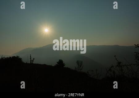 Il sole del mattino splende sul monte Naag Tibba, situato a Uttarakhand, India, creando un'atmosfera nebbiosa, creando un'atmosfera nebbiosa. Foto Stock