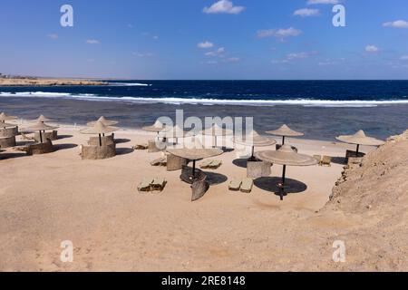 Gli ombrelloni di paglia dai raggi del sole si trovano sulla spiaggia sabbiosa Foto Stock