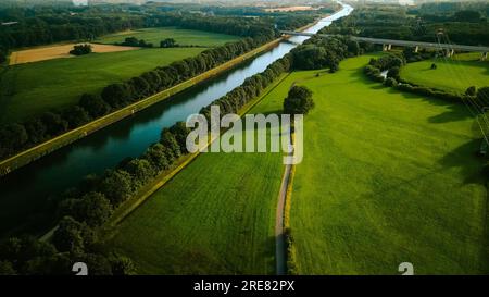 D'estate, vista aerea con droni, fiume navigabile con ponti, campi agricoli e foreste e case contadine nella campagna tedesca. Foto Stock