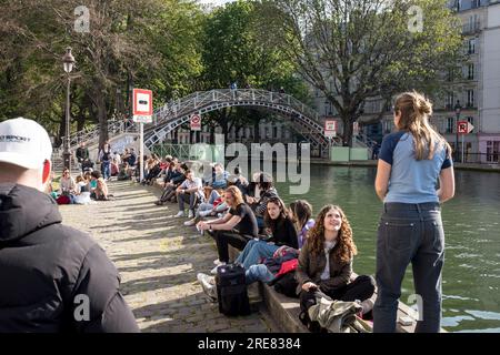 I giovani si ritrovano accanto al canale nell'emergente area del Canal Saint Martin di Parigi, in una splendida giornata primaverile. Foto Stock