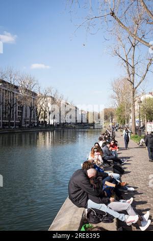 Persone di tutte le età si divertono all'aria aperta lungo il canale nell'emergente area di Canal Saint Martin di Parigi, in una splendida giornata primaverile. Foto Stock