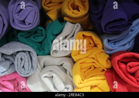 Una foto ravvicinata di un telo da spiaggia colorato arrotolato e messo in mostra su uno scaffale del negozio. Foto Stock
