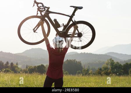 Giovane donna professionista bicyclist durante la corsa su strada, movimento continuo con massimo sforzo, vista ravvicinata. Foto Stock