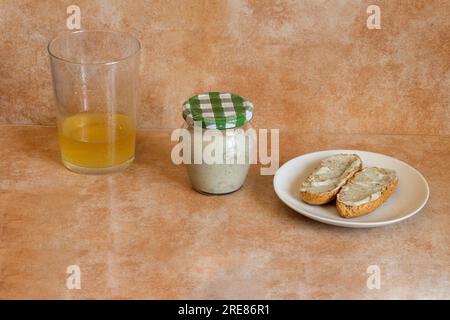 Formaggio Cabrales cremoso in un piccolo vasetto trasparente, abbinato a uno shot in un bicchiere di sidro e a pane integrale tostato con formaggio Cabrales. TR Foto Stock