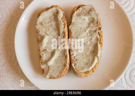 Vista dall'alto dei panini tostati integrali sparsi con crema di formaggio Cabrales su un piatto, accompagnati da un tovagliolo come sfondo. Combinazione di gusto Foto Stock